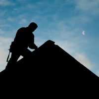 Contractor In Silhouette Working On A Roof Top